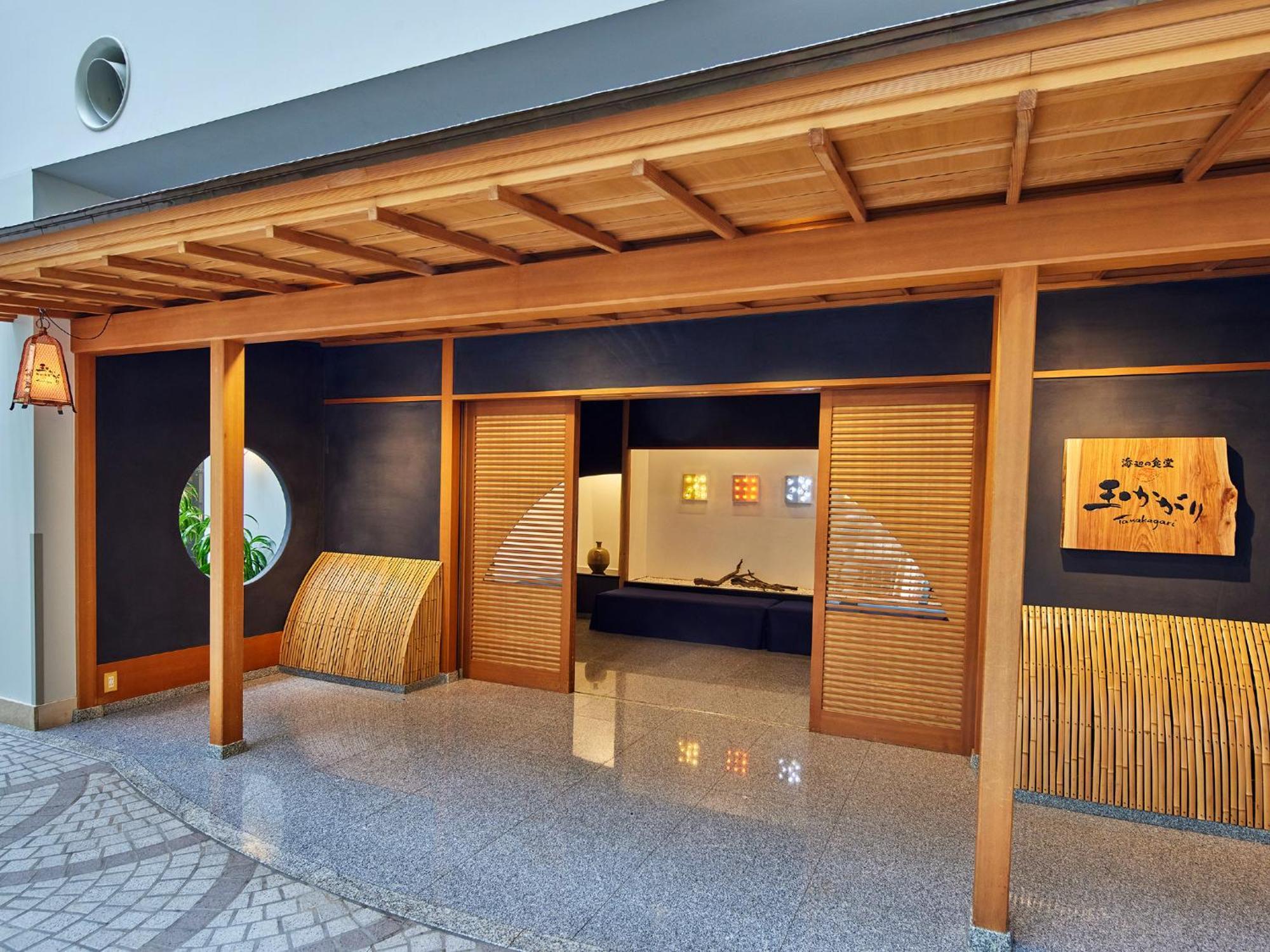 Grand Nikko Tokyo Bay Maihama Hotel Urayasu Ngoại thất bức ảnh The photo shows the entrance of a building, designed in a traditional Japanese style. It features a wooden structure with a large overhanging roof and sliding doors. The entrance is flanked by rounded windows, and there's a decorative sign with Japan