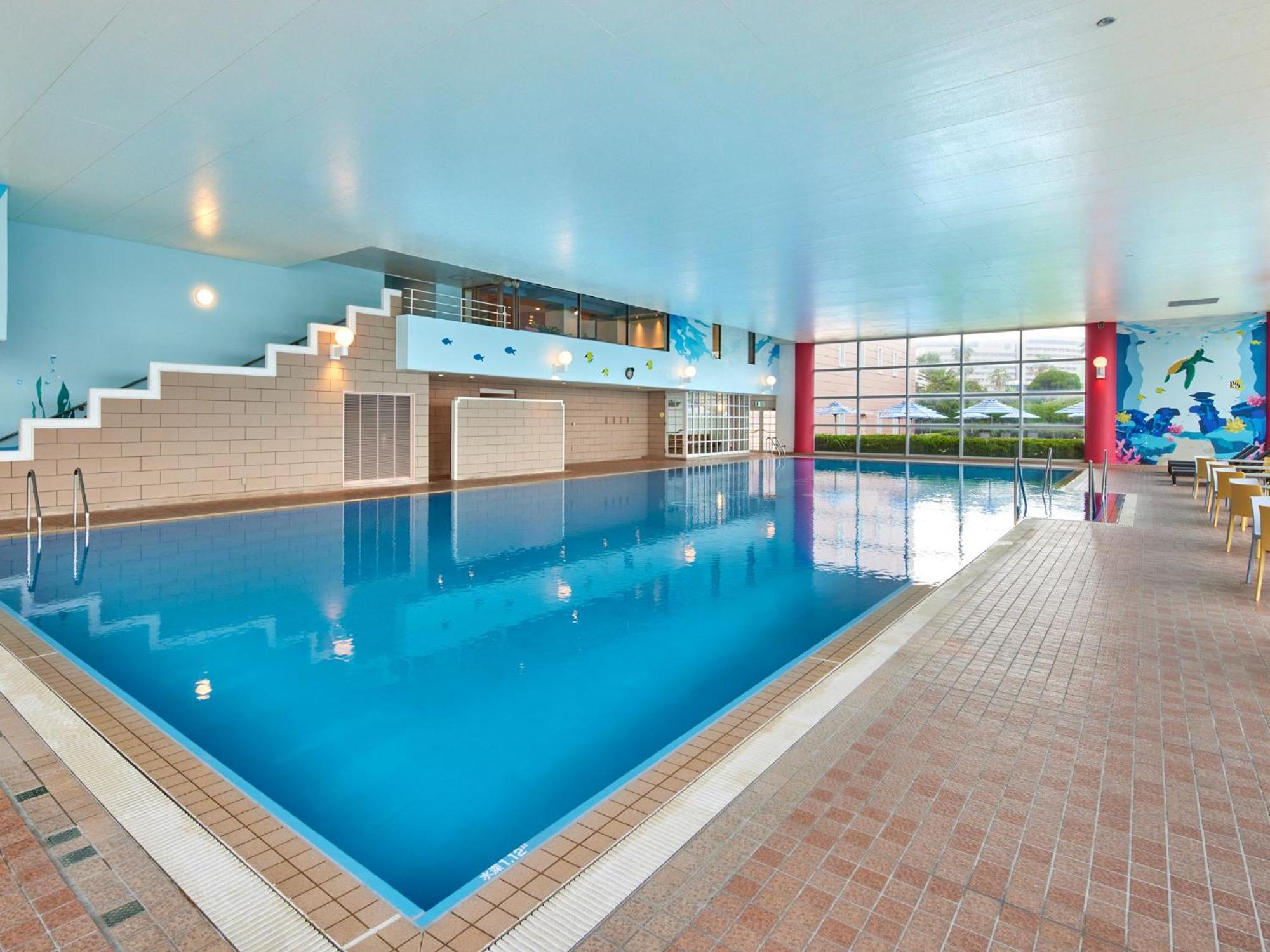 Grand Nikko Tokyo Bay Maihama Hotel Urayasu Ngoại thất bức ảnh The photo shows an indoor swimming pool area with a spacious design. The pool has a clear blue water surface and is surrounded by a tiled deck. On one side of the pool, there are steps leading into the water, and there are large windows letting in na