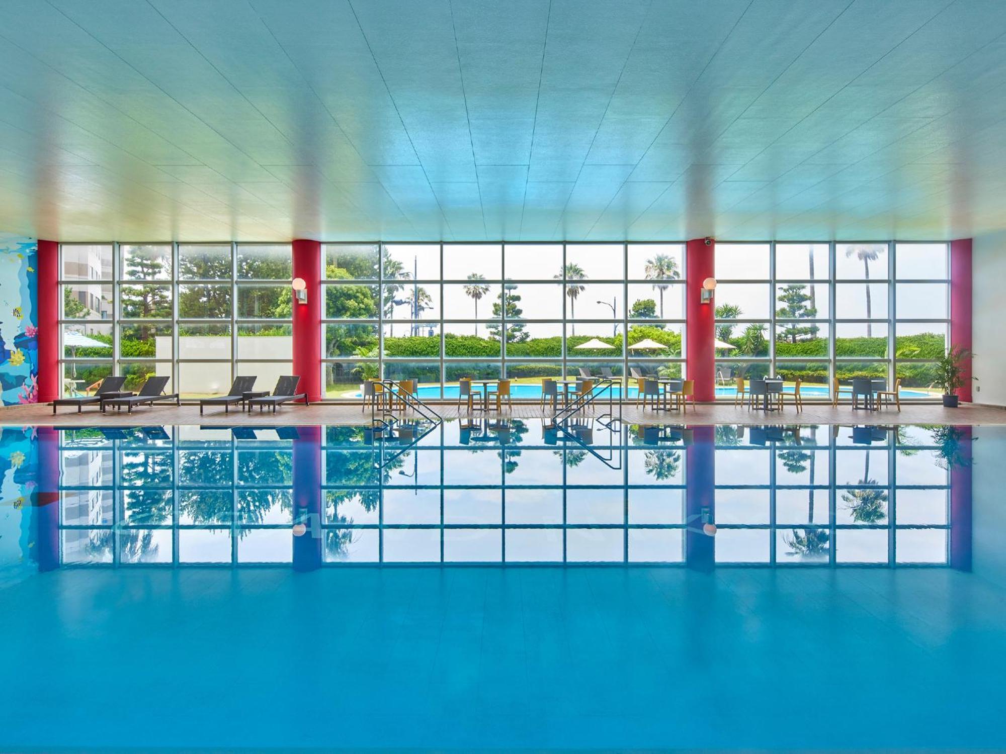 Grand Nikko Tokyo Bay Maihama Hotel Urayasu Ngoại thất bức ảnh The photo shows an indoor swimming pool with bright blue water. The pool area is spacious, characterized by large windows that allow natural light to flood in, creating a vibrant atmosphere. The walls are painted in a soft color, with accents of red.