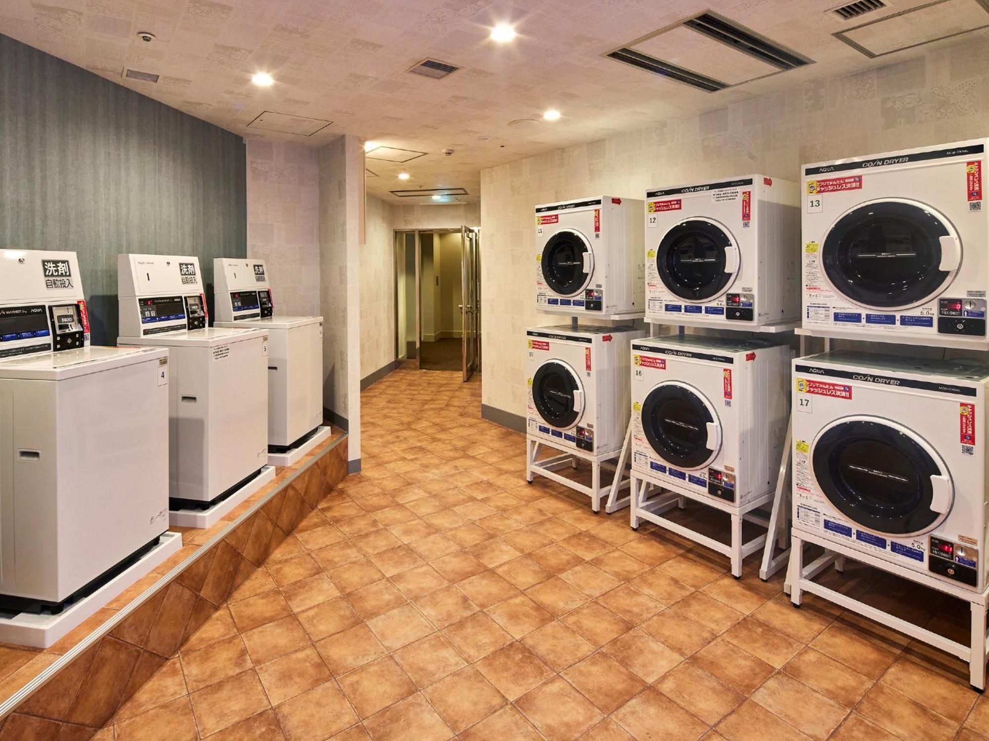 Grand Nikko Tokyo Bay Maihama Hotel Urayasu Ngoại thất bức ảnh The photo shows a laundry room with several washing machines and dryers. On the left side, there are five white washing machines, and on the right side, there are four dryers. The machines are arranged in a clean, tiled space with a neutral-colored w